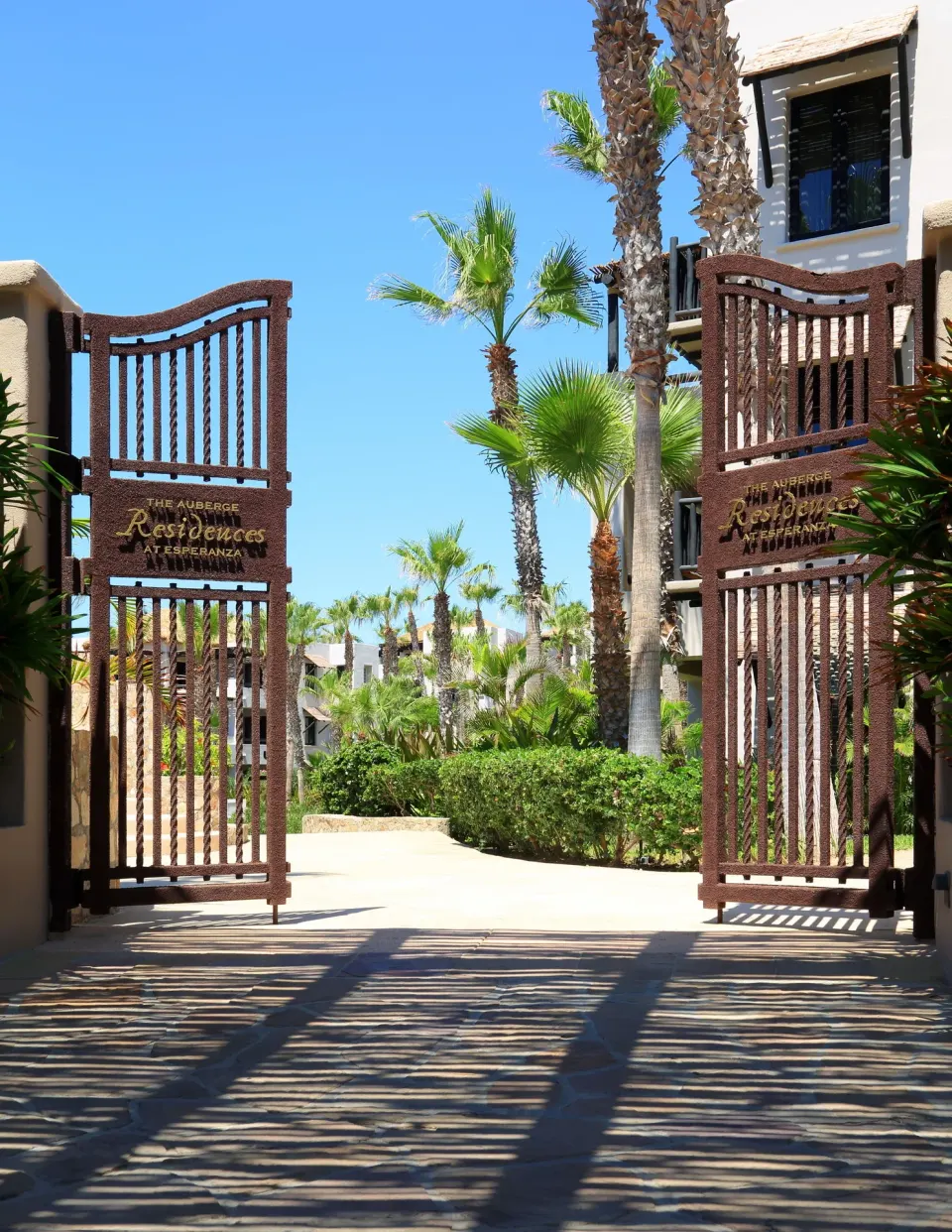 Open residence gates framed by palms and resort buildings at Esperanza.