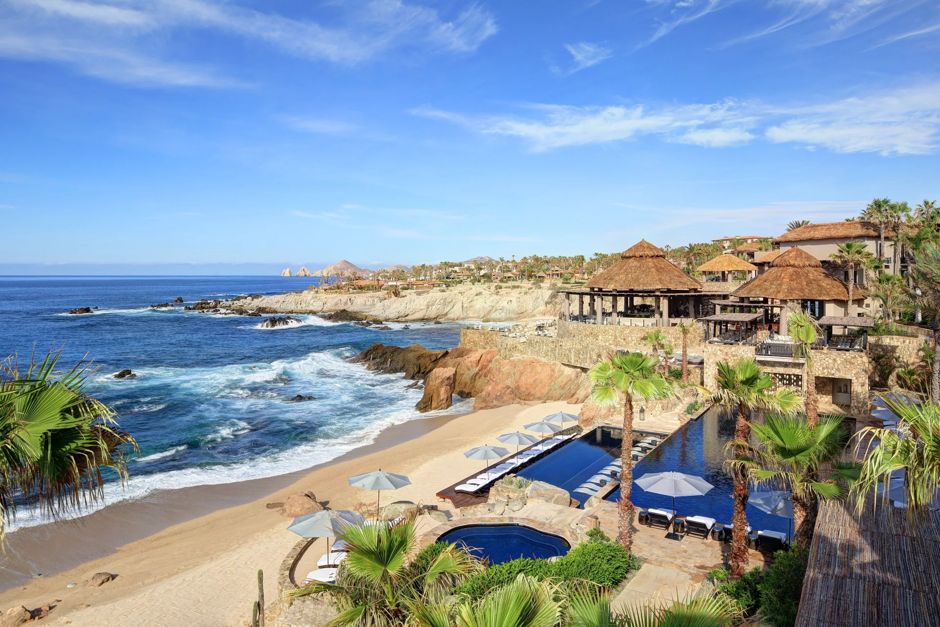 Sunny view of the beach, pool terraces, palms, and ocean at Esperanza.