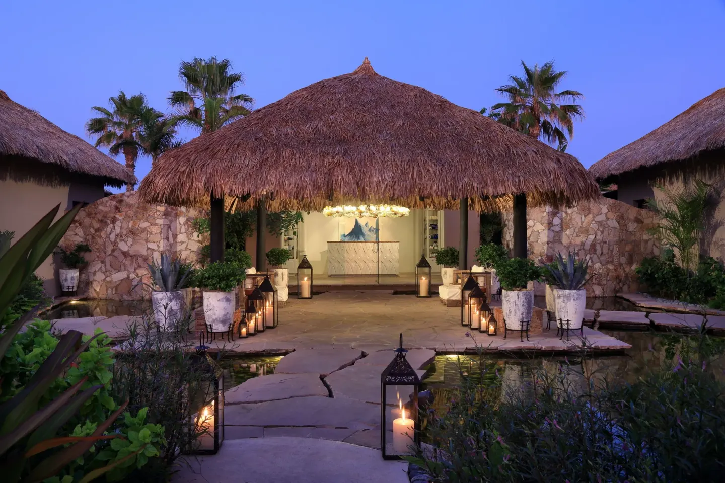 Thatched spa reception pavilion with lanterns at dusk at Esperanza.