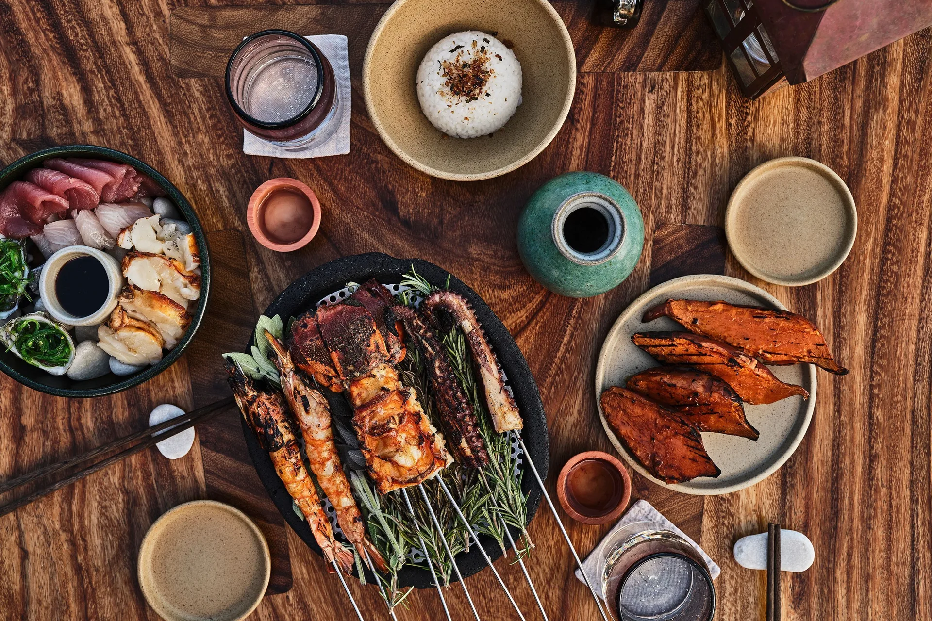 Seafood, rice, grilled vegetables, and drinks set on a wooden table at Esperanza.