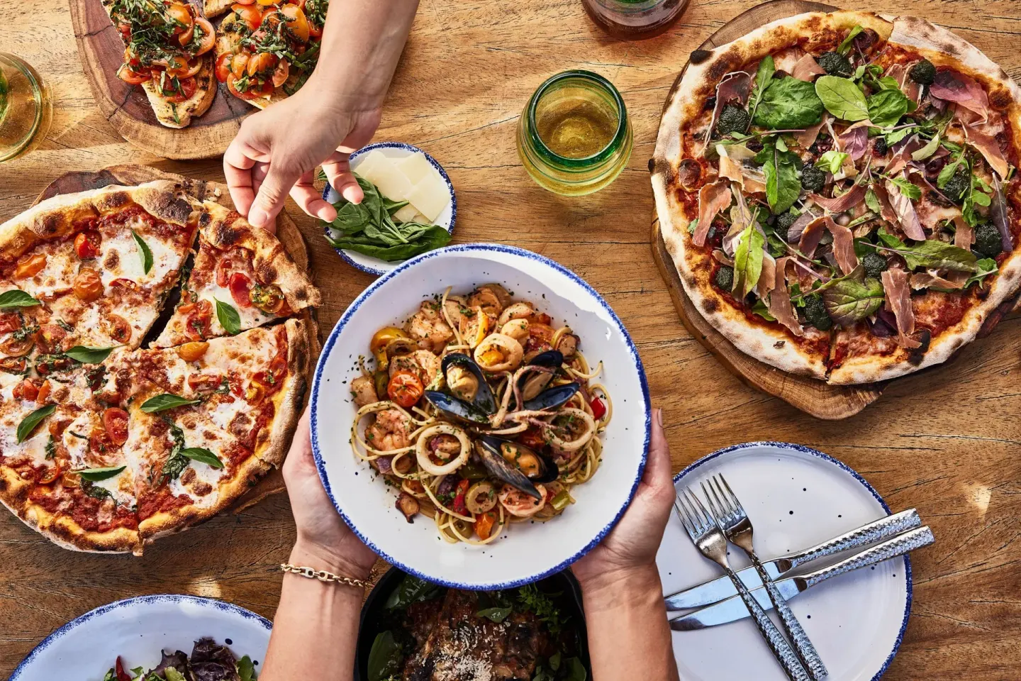 Pizzas, seafood pasta, salad and bruschetta on a wooden table at Esperanza.