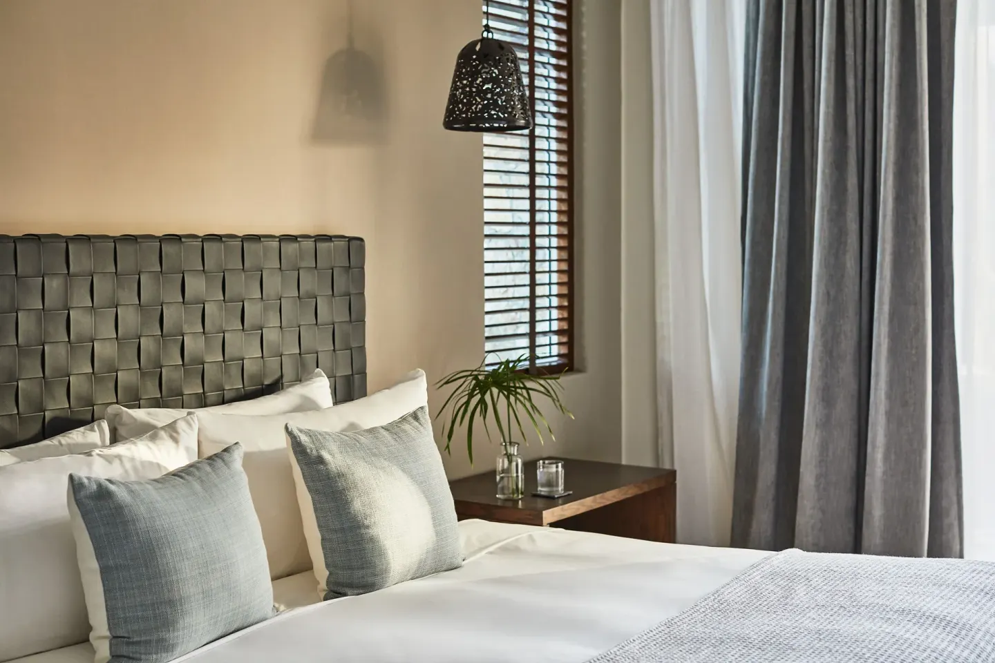 Close view of a bed, woven headboard, and bedside table in a casona bedroom at Esperanza.