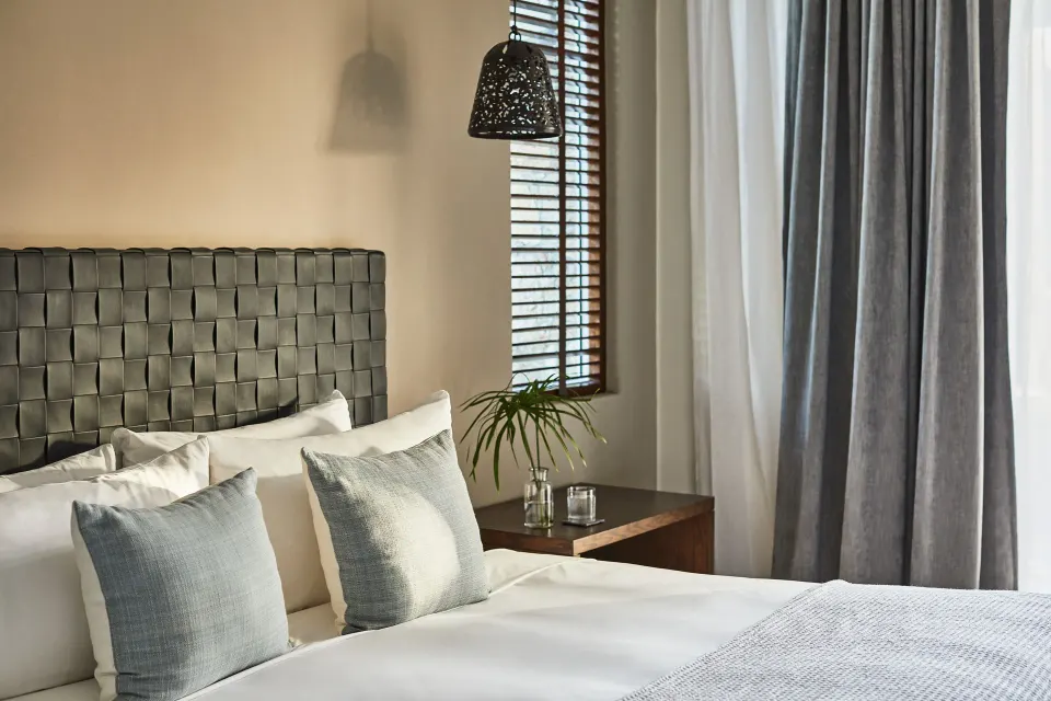 Close view of a bed, woven headboard, and bedside table in a casona bedroom at Esperanza.