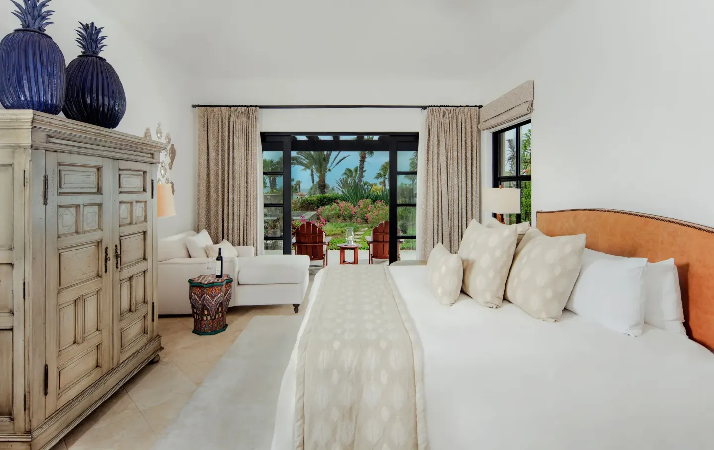 Guest room with king bed, armoire, armchair, and garden terrace at Esperanza.