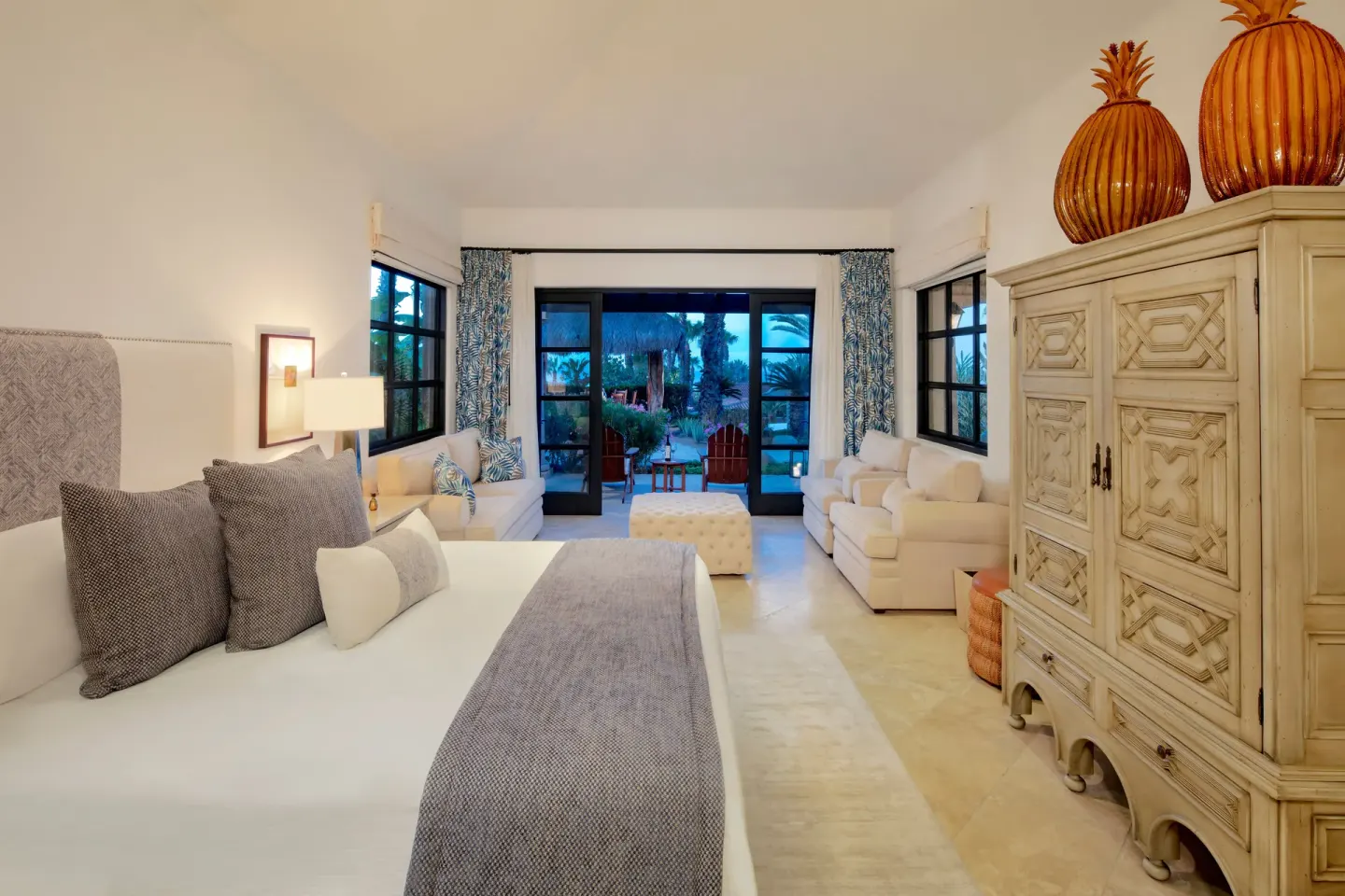Guest room with king bed, sofas, armoire, and patio doors at Esperanza.