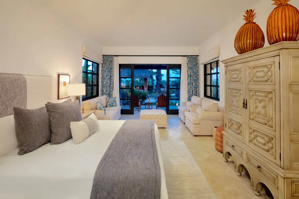 Guest room with king bed, sofas, armoire, and patio doors at Esperanza.