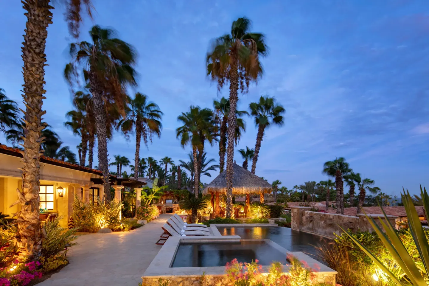 Hacienda pool and hot tub with palms and loungers at dusk at Esperanza.