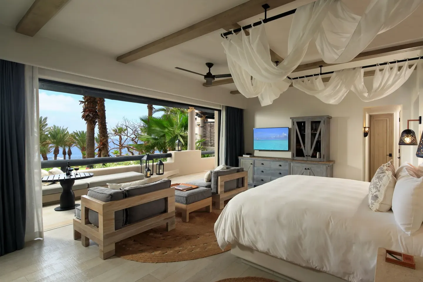 Ocean View casita at Esperanza with a king bed, sitting area, terrace and ocean beyond palms.