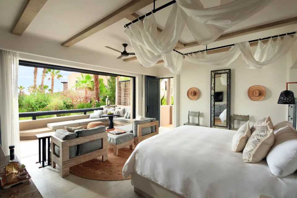 Ocean View casita at Esperanza with a bed, lounge chairs and terrace opening to palms.
