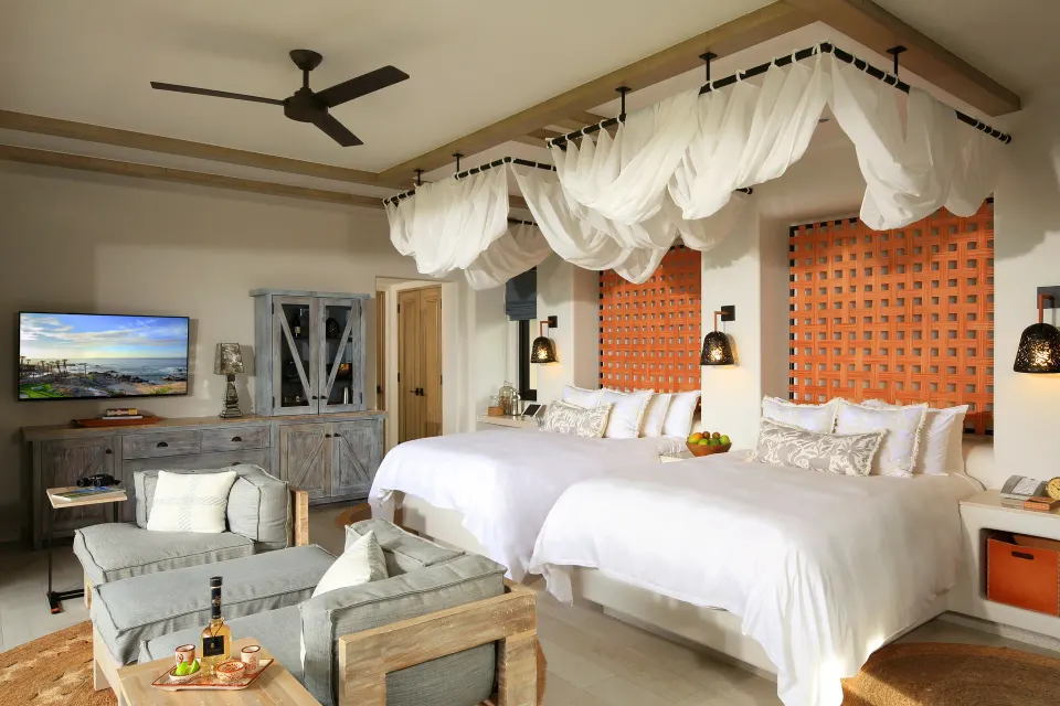 Ocean View casita at Esperanza with two beds, lounge seating, TV and draped canopy fabric.