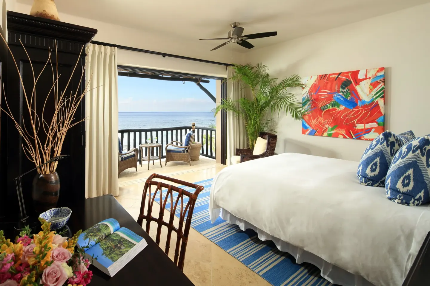 Villa bedroom with king bed, desk, and balcony seating by the ocean at Esperanza.