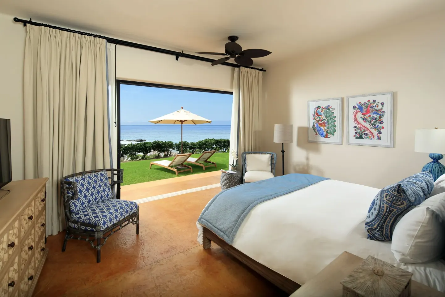 Villa bedroom with king bed, lawn terrace, umbrella, and ocean view at Esperanza.