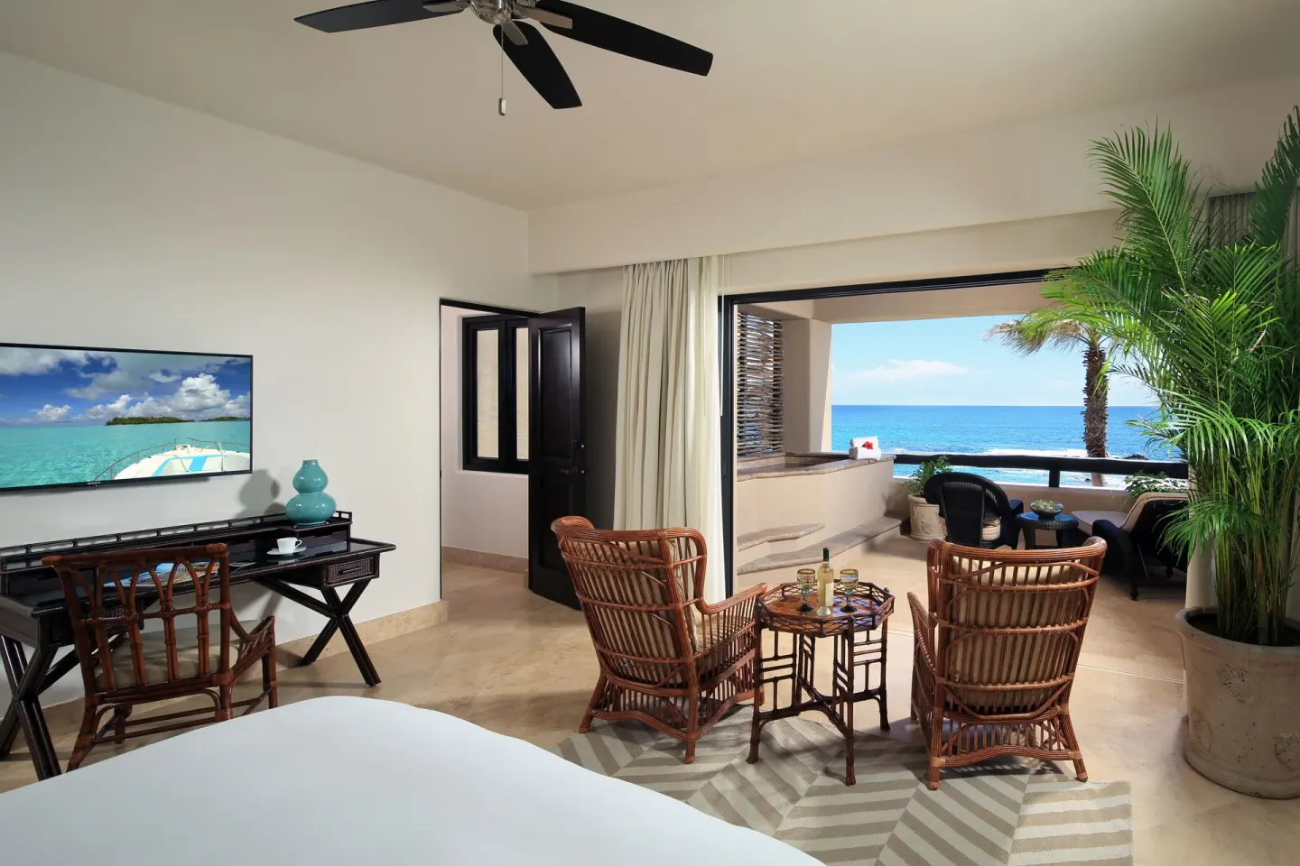 Villa bedroom sitting area with ocean-view terrace and TV at Esperanza.