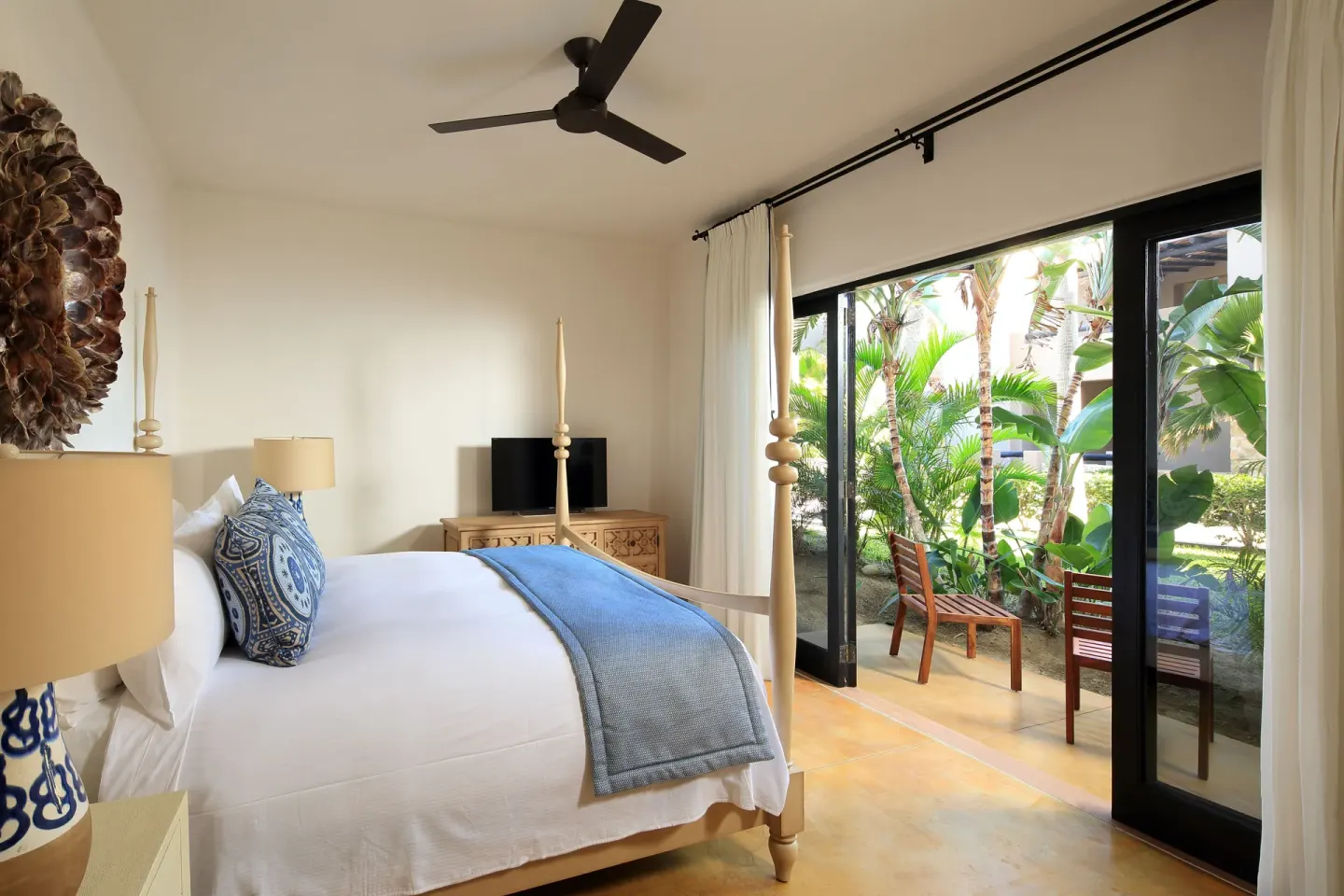 Villa bedroom with a four-poster bed and patio doors opening to greenery at Esperanza.