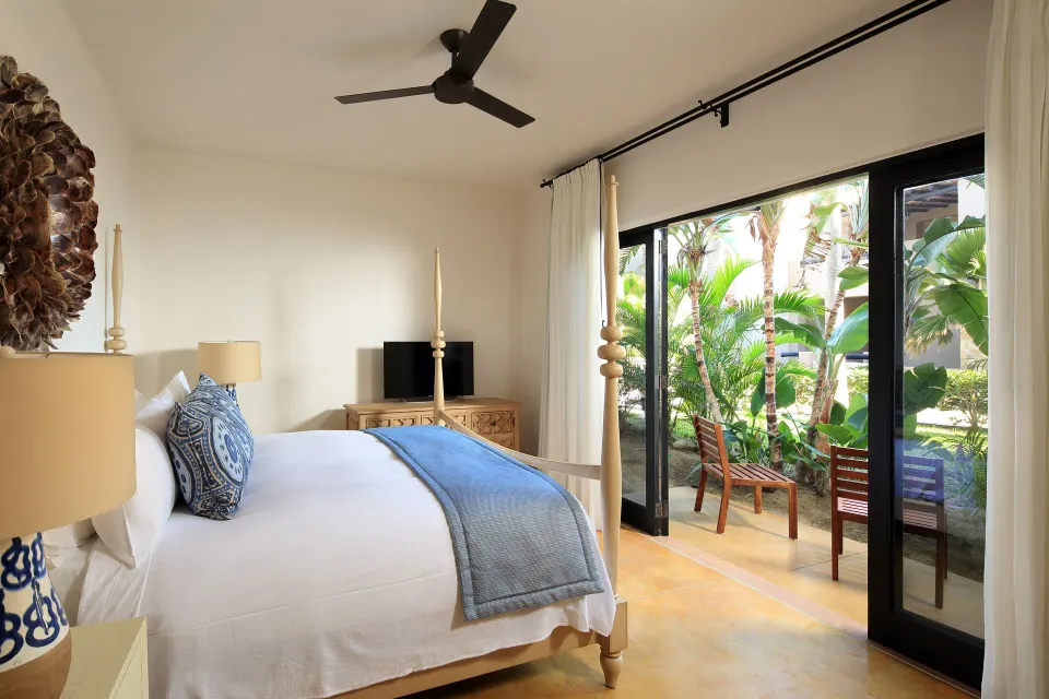 Villa bedroom with a four-poster bed and patio doors opening to greenery at Esperanza.