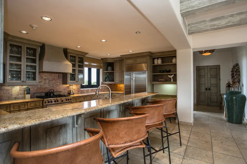 Villa kitchen with stone island, bar stools, and wood cabinetry at Esperanza.