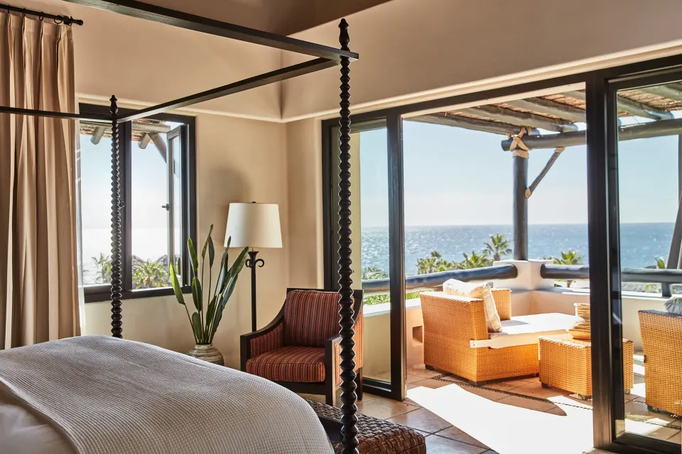 A villa bedroom at Esperanza opens to a furnished terrace with a broad ocean view.