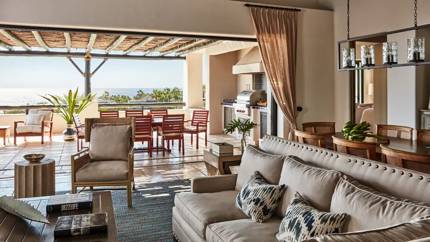 A villa living area at Esperanza opens to a terrace with dining chairs and ocean beyond.