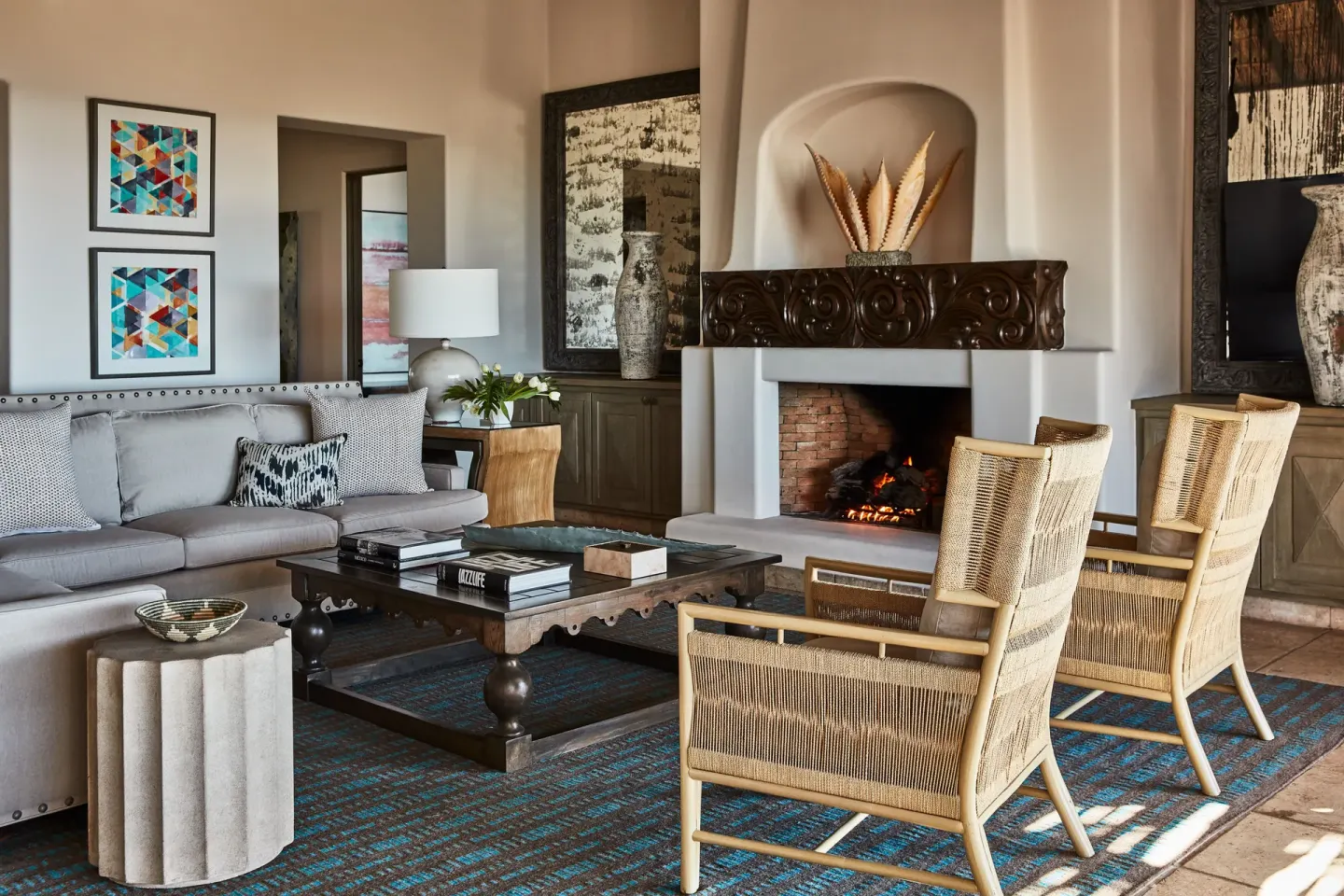 A villa living room at Esperanza has a sofa, woven chairs, coffee table, and lit fireplace.