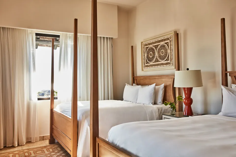 Two wood-frame beds in a villa bedroom at Esperanza with white linens and wall art.