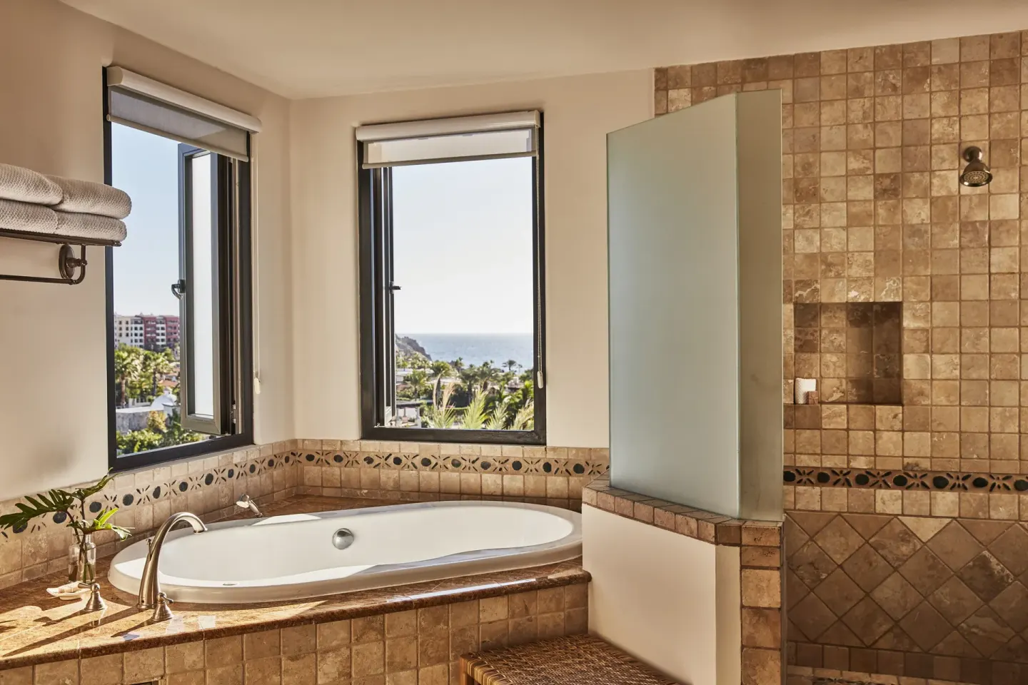 Villa bathroom with soaking tub, tiled shower, and ocean view windows at Esperanza.