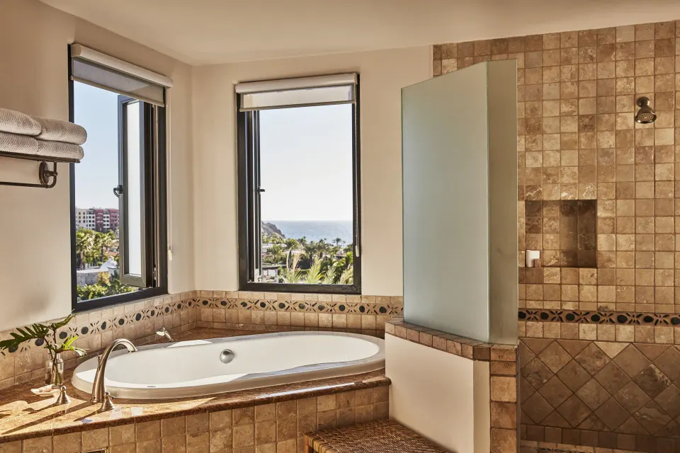 Villa bathroom with soaking tub, tiled shower, and ocean view windows at Esperanza.