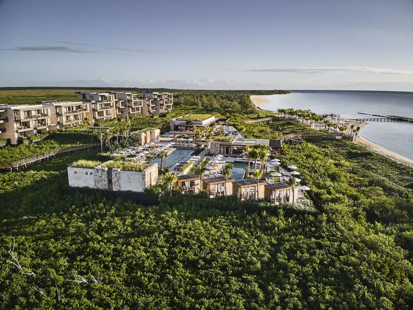Aerial view of resort buildings, pools, beach and coastline at Etéreo, Auberge Collection.