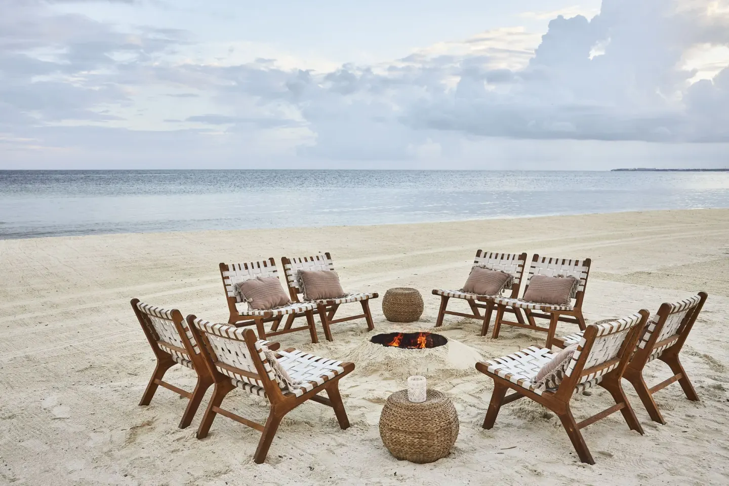 Beach chairs encircle a fire pit on the sand at Etéreo, Auberge Collection.