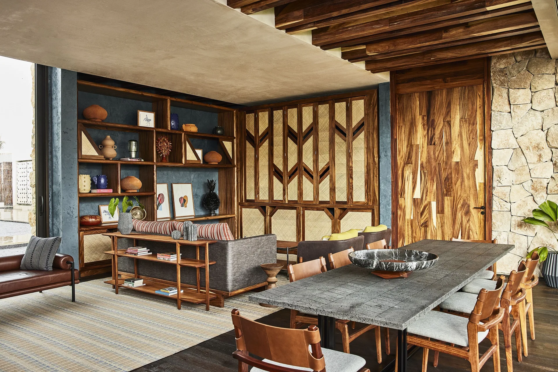 Wood-paneled lounge and dining table with stone wall at Etéreo, Auberge Collection.
