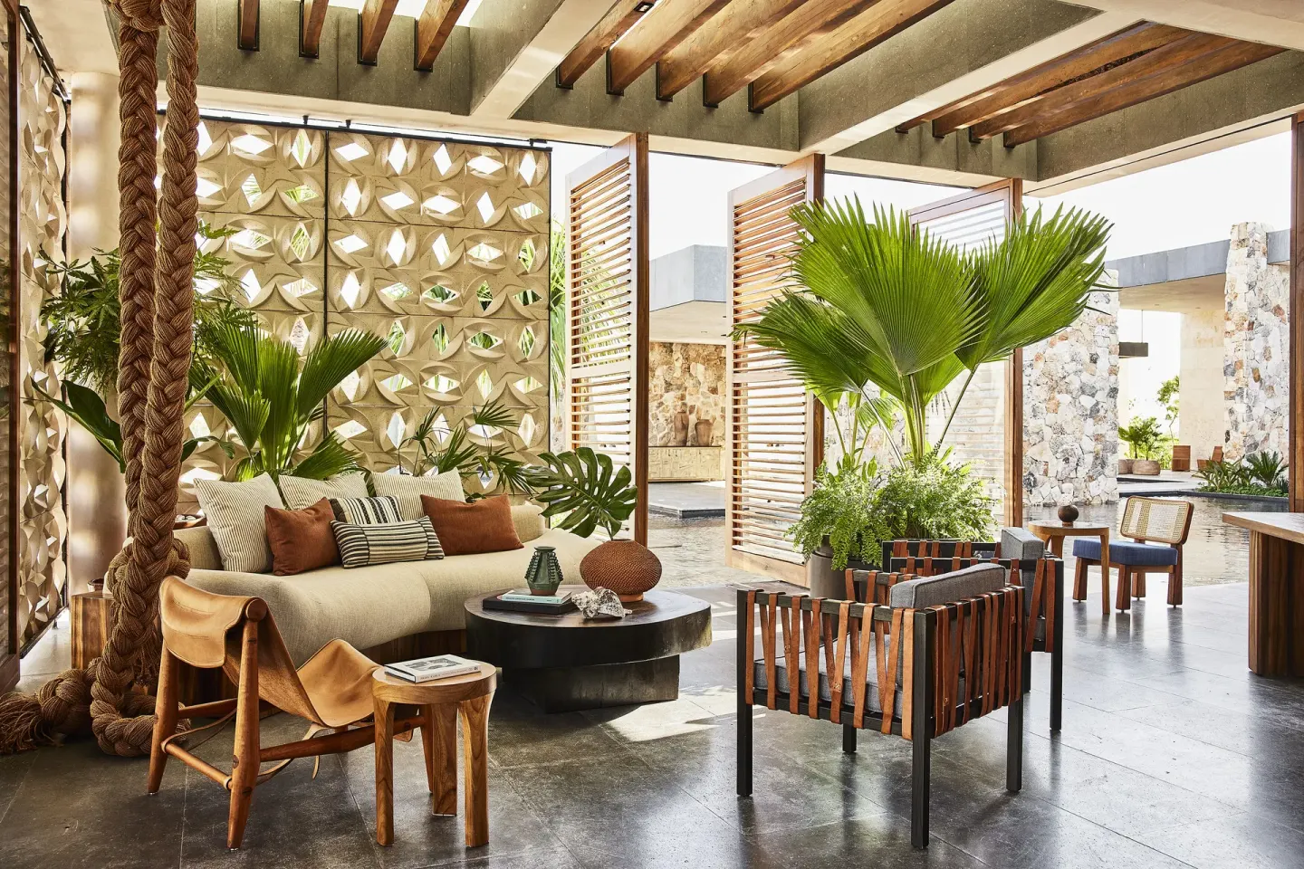 Open-air lounge with woven wall panels and tropical plants at Etéreo, Auberge Collection.