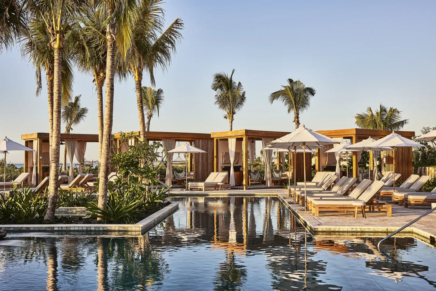 Poolside loungers, umbrellas, palms, and cabanas at Etéreo, Auberge Collection.