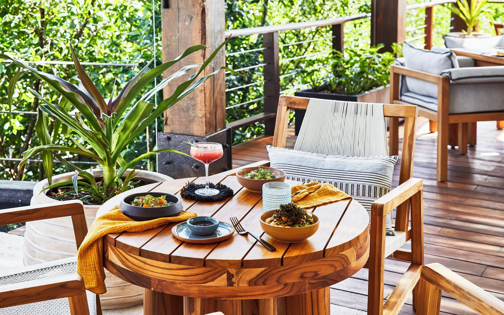 Round terrace table with small plates and a cocktail at Etéreo, Auberge Collection.