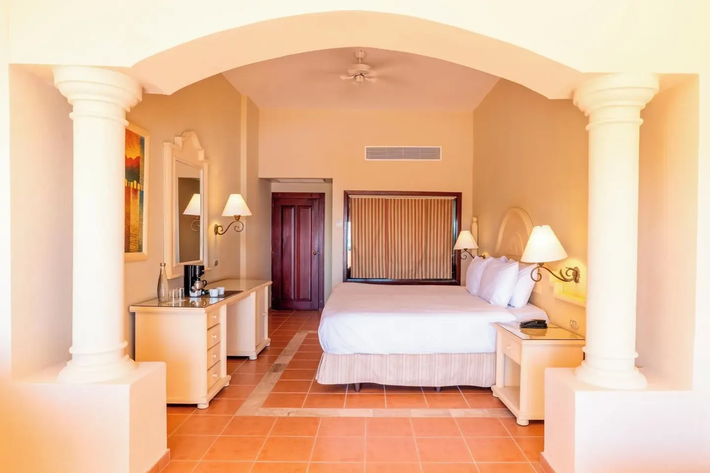 Guest room king bed framed by cream columns at Eurostars Grand Cayacoa.