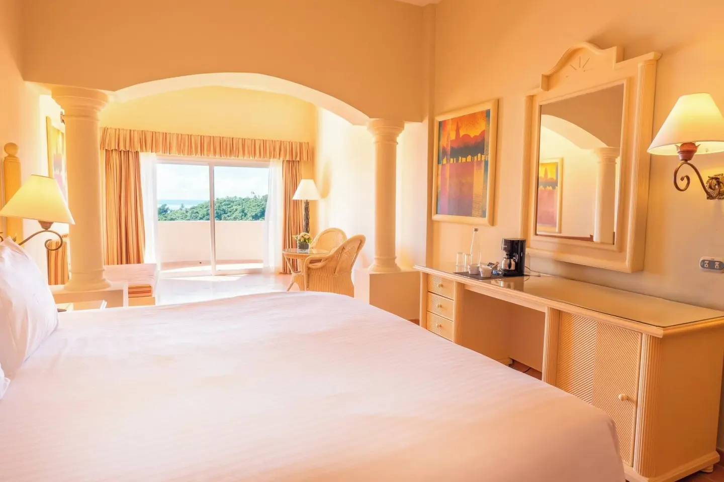 Guest room king bed with dresser and balcony beyond at Eurostars Grand Cayacoa.