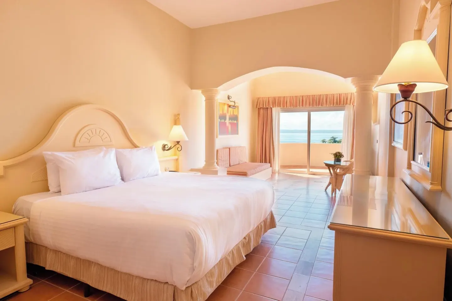 Guest room king bed with seating area and balcony view at Eurostars Grand Cayacoa.