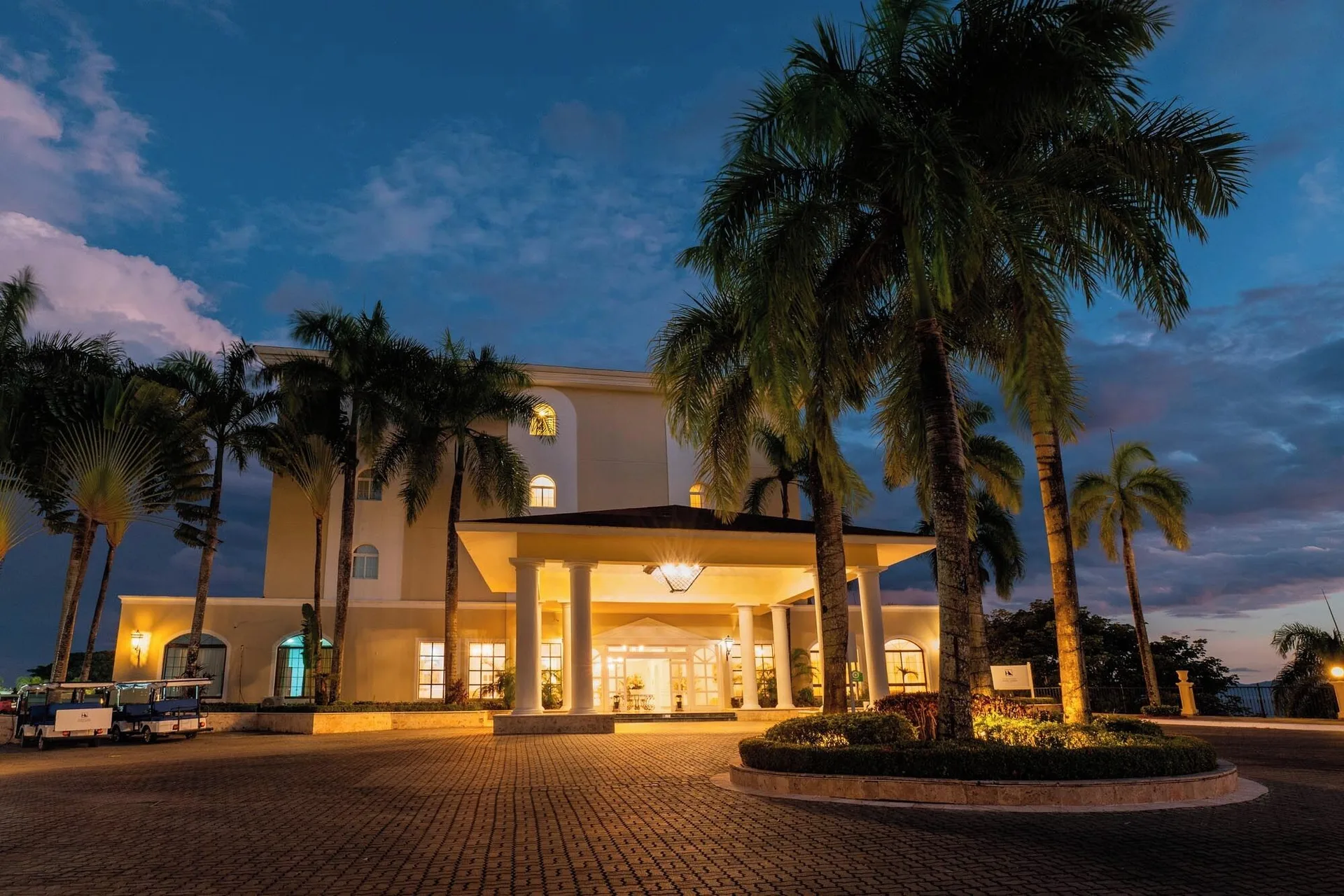 Nighttime resort entrance with palms and lights at Eurostars Grand Cayacoa.