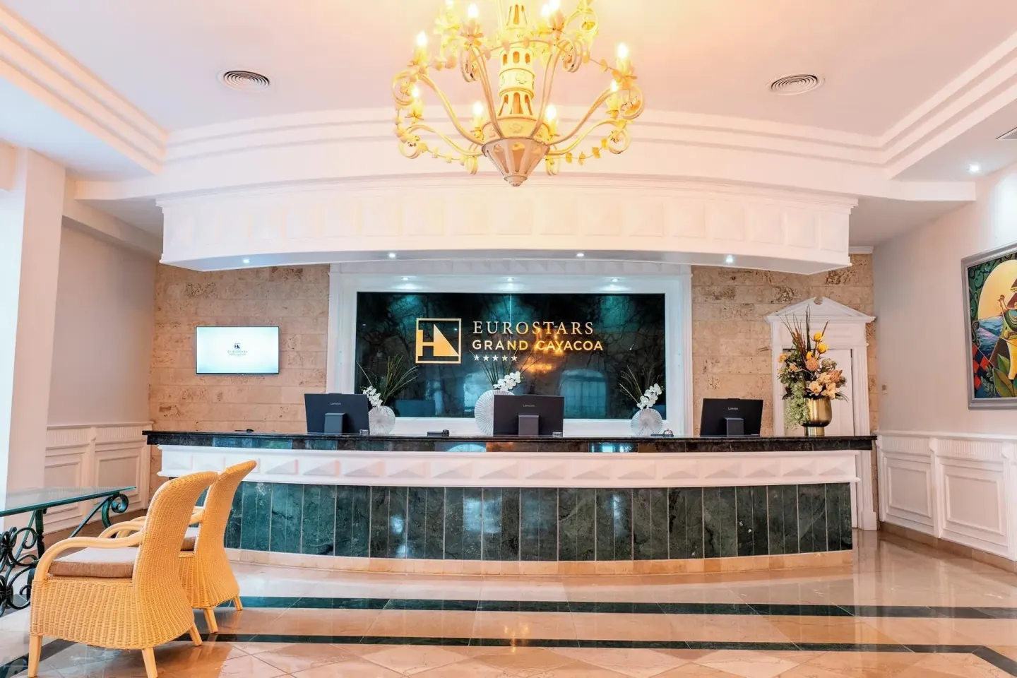 Reception counter with hotel sign and chandelier at Eurostars Grand Cayacoa.