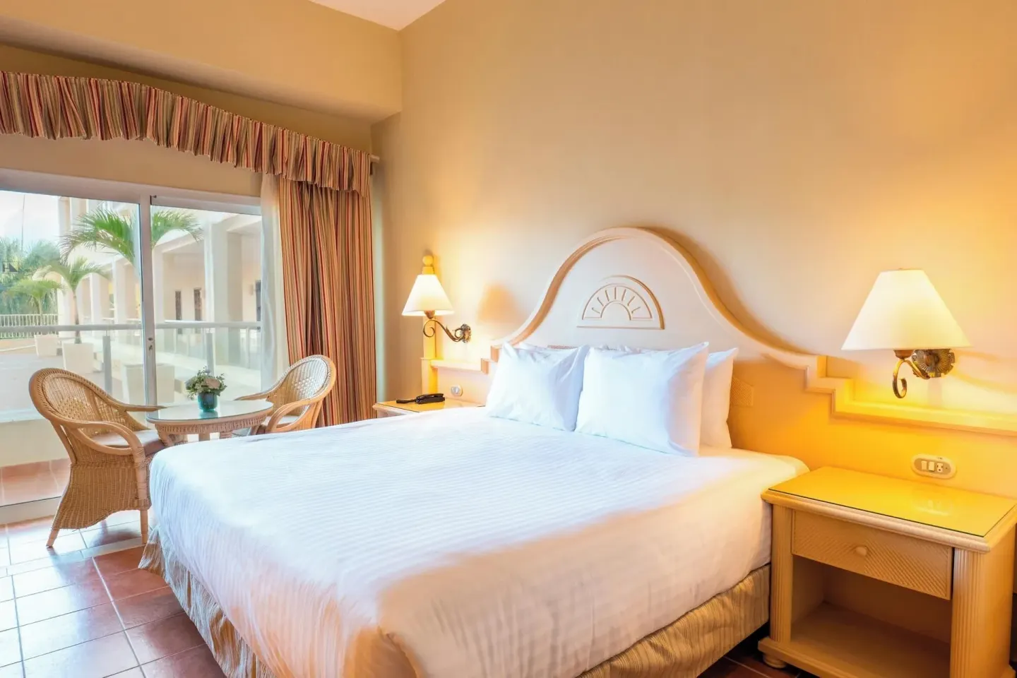 Deluxe Room with king bed, bedside lamps, and balcony seating at Eurostars Grand Cayacoa.