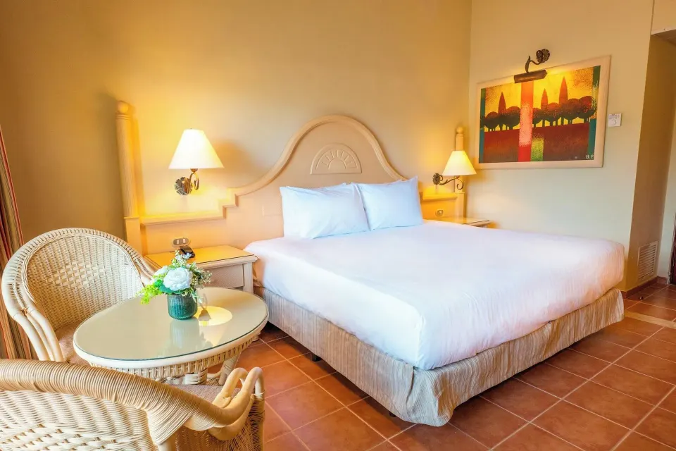 Deluxe Room king bed with wicker chairs and round table at Eurostars Grand Cayacoa.
