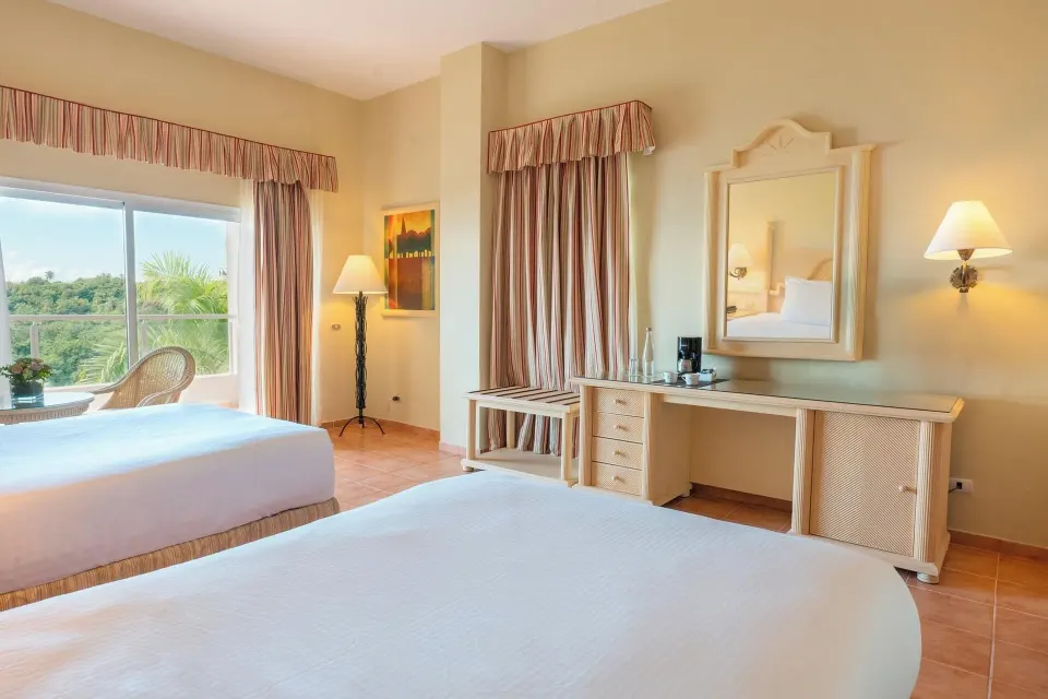 Deluxe Room with two beds, vanity, balcony doors, and greenery view at Eurostars Grand Cayacoa.