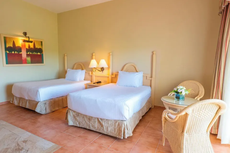 Deluxe Room with two beds and a wicker table set by the curtains at Eurostars Grand Cayacoa.
