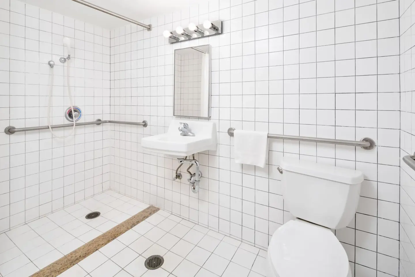 Accessible tiled bathroom with roll-in shower at Ewa Hotel Waikiki.