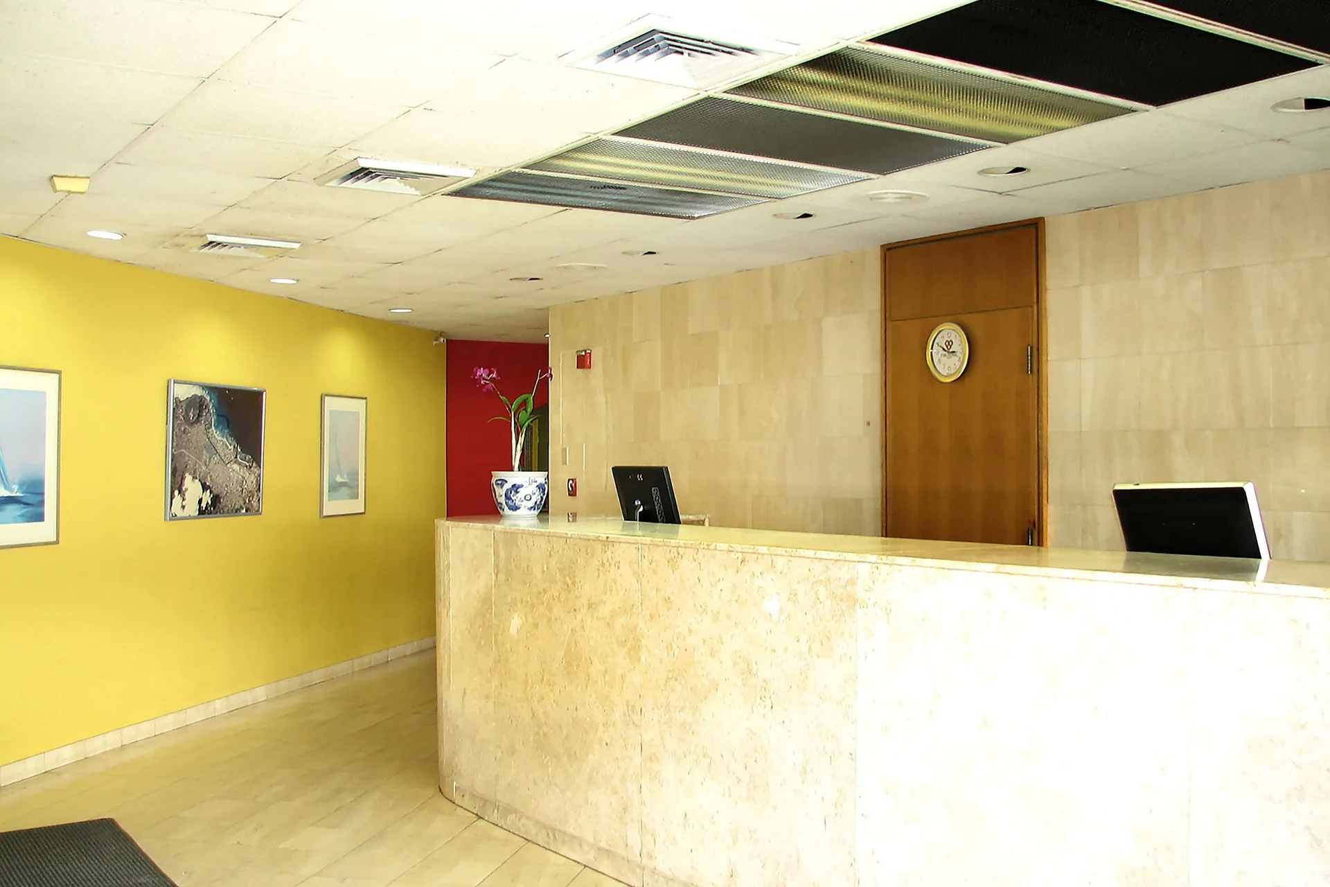 Front desk with marble counter and yellow wall art at Ewa Hotel Waikiki.