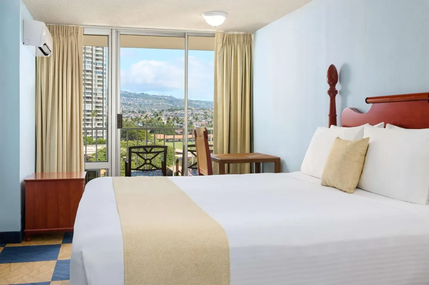 Guest room with one bed, desk, and balcony view at Ewa Hotel Waikiki.
