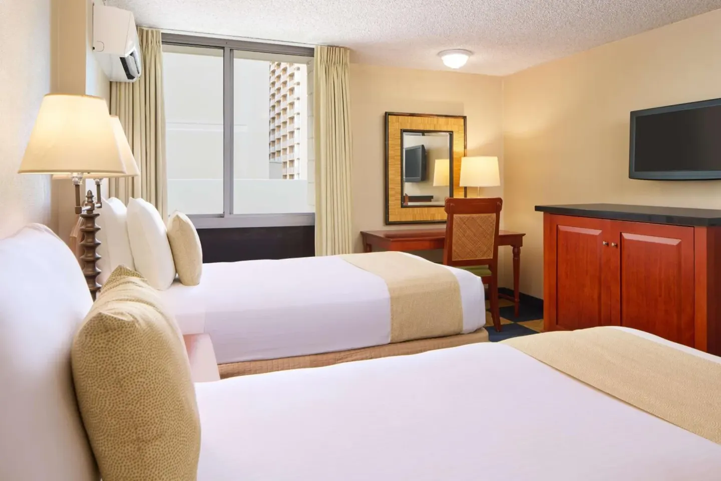 Guest room with two double beds, desk, and TV at Ewa Hotel Waikiki.