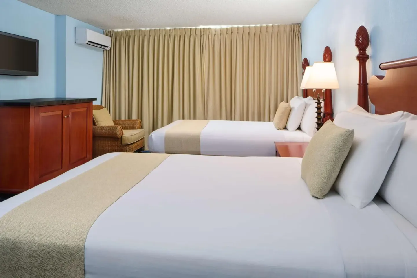Guest room with two double beds and lounge chair at Ewa Hotel Waikiki.