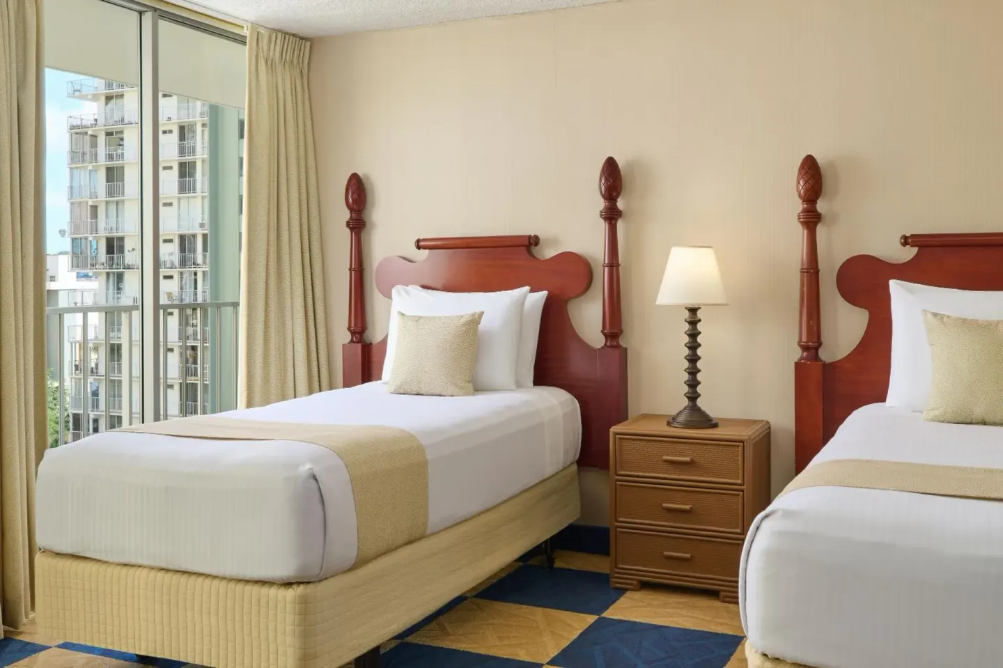 Guest room with two twin beds and balcony doors at Ewa Hotel Waikiki.