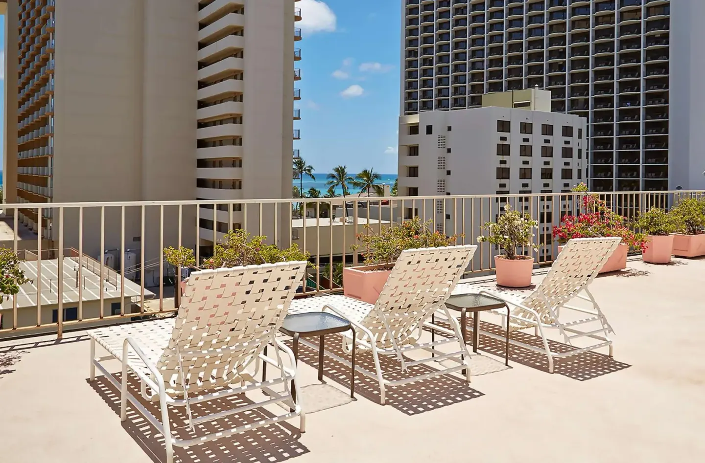 Rooftop sundeck with lounge chairs and a distant ocean view at Ewa Hotel Waikiki.