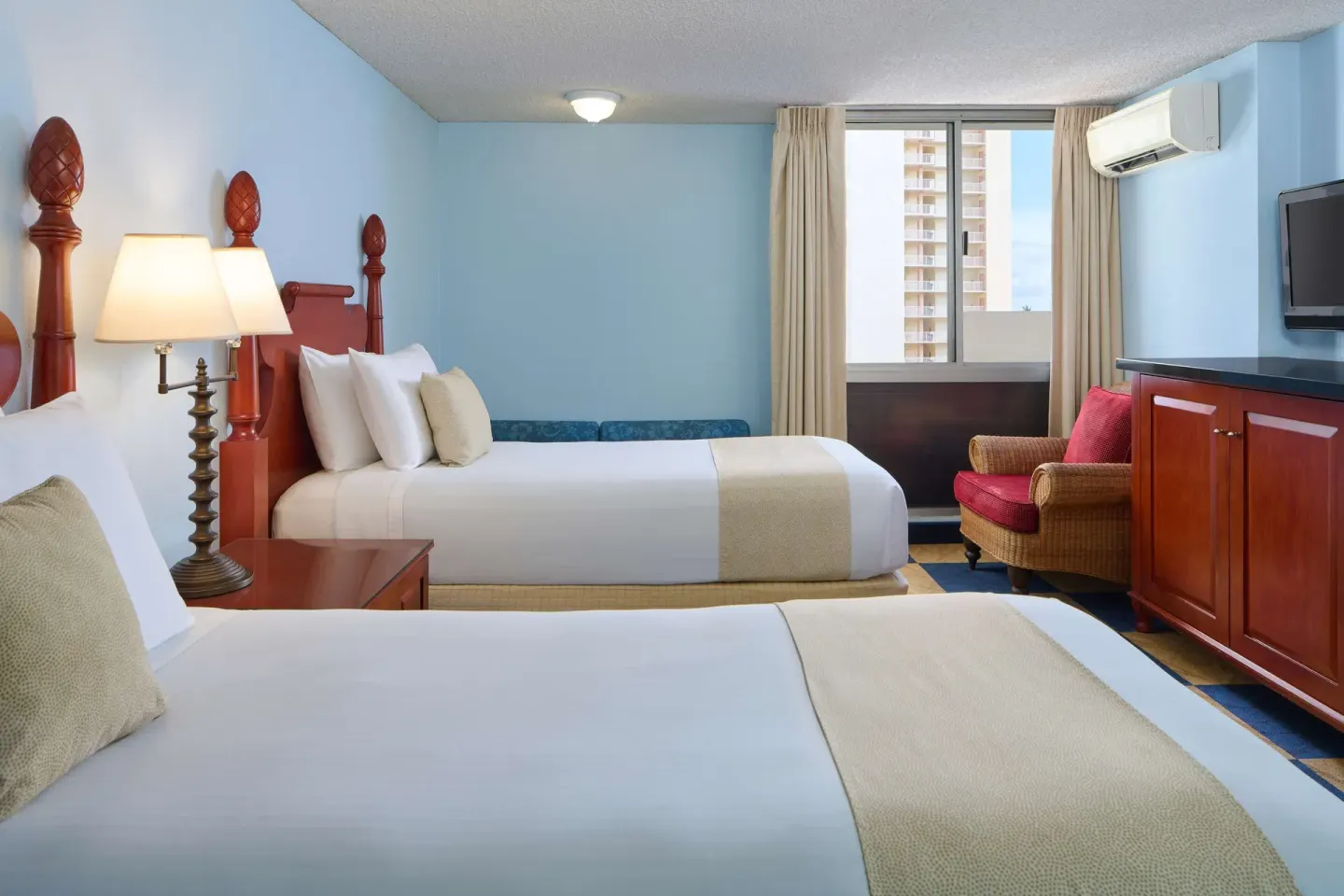 Studio kitchenette room with two beds, cabinet, TV, and chair at Ewa Hotel Waikiki.