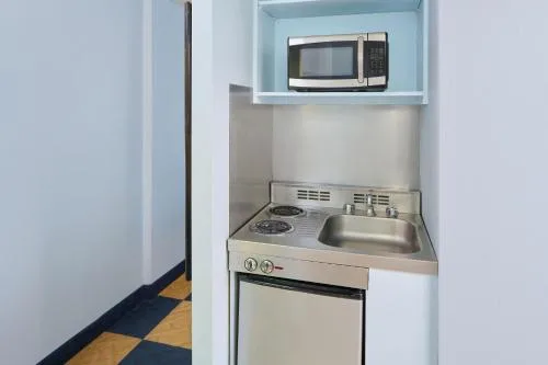 Studio kitchenette with sink, cooktop, and microwave at Ewa Hotel Waikiki.